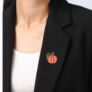 Broche citrouille d'Halloween en émail orange et strass sur le revers d'un costume noir