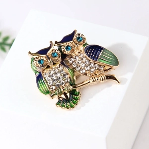 Elegant owl brooch with blue enamel and crystal inlay on a golden branch base
