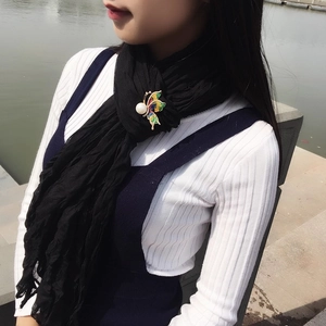 Détail de la broche papillon en émail coloré avec perle sur une écharpe noire