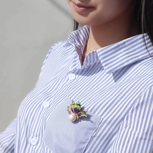 Vue détaillée de la broche papillon de luxe avec ailes en émail coloré et grande perle
