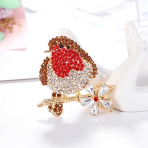 Exquisite bird brooch with colorful rhinestones and gold flower on a white stand