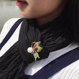 Vue détaillée de la broche papillon en émail coloré avec une grande perle élégante