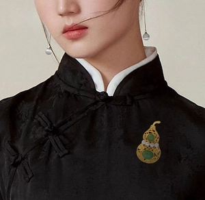 Detailansicht der matten Gold-Kalebassen-Brosche mit Jade und Perlen auf schwarzem Qipao