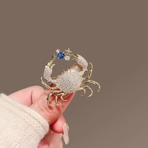 Detailed close-up of a crab brooch with sparkling zircons and a deep blue gemstone