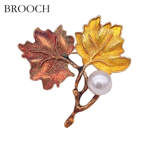 Detail of maple leaf brooch with enamel gradient colors and a large round white pearl