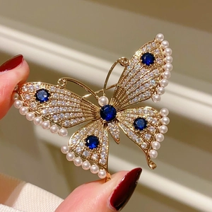 Macro detail of butterfly brooch with blue gems, clear rhinestones and pearl trim