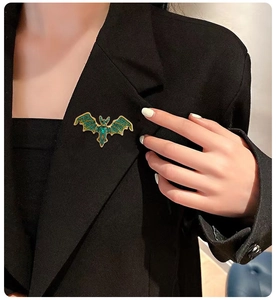 Detail der Fledermaus-Brosche mit grünen Kristallen an einem schwarzen Anzug