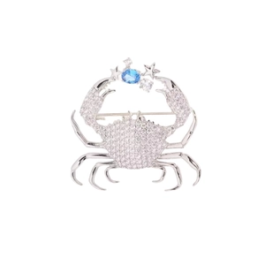 Detailed macro view of silver crab brooch featuring inlaid blue stone and zircon stars