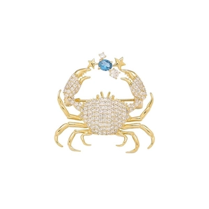 Close-up detail of crab brooch with blue gemstone and white diamonds on gold metal
