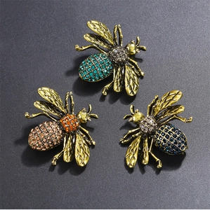 Detailed close-up of three bee brooches with colorful rhinestones in vintage gold setting