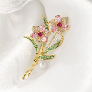 Detail of rose brooch with pink crystals, green leaves, and white pearl on silk