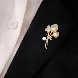Élégante broche fleur dorée avec perles et strass sur le revers d'un tailleur noir