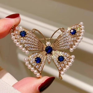 Luxurious gold butterfly brooch with pearls, diamonds, and blue sapphire accents