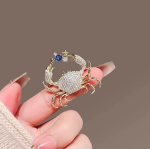 Exquisite gold crab brooch with white zircon micro-paving and a dark blue center stone