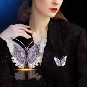 Broche papillon argentée avec gemmes violettes et pavé de zircons sur une veste noire