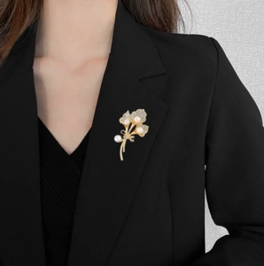 Élégante broche feuille de ginkgo dorée avec perles et cristaux sur un revers noir