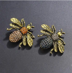 Macro detail of vintage gold bee brooches with colorful rhinestones and etched wing patterns