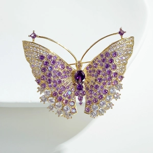 Detail van een vlinderbroche met goud metaal en paarse gradiënt kristallen