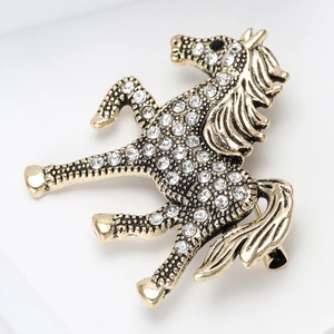 Detailed close-up of a vintage horse brooch with white rhinestones and gold-tone finish