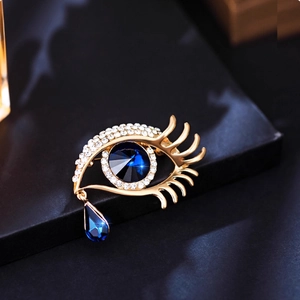 Elegant gold evil eye crystal brooch with sparkling rhinestones and blue teardrop pendant