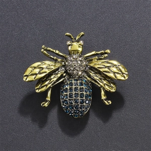 Macro detail of bee brooch with blue rhinestones and vintage gold textured wings