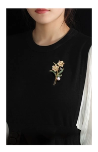 Detail of rose flower brooch with sparkling rhinestones and a white pearl on black fabric