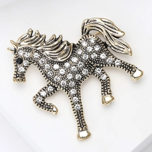 Detailed close-up of retro horse brooch with white rhinestones and antique gold finish
