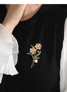 Detail of rose brooch with champagne crystals and pearl on black blazer
