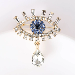 Detailed view of the gold Evil Eye brooch with blue rhinestones and crystal drop pendant