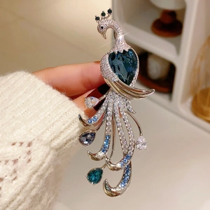 Macro shot of peacock brooch with heart-shaped blue gemstone and sparkling crystals