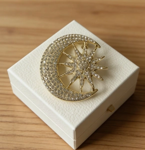 Macro detail of sun and moon brooch with crystals on a white jewelry box display
