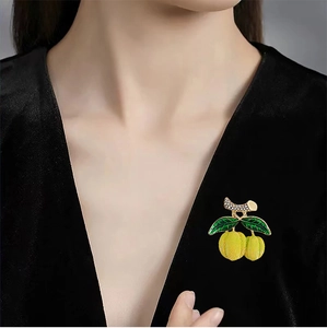 Détail de la broche fruit jaune avec émail vert et strass sur un costume en velours noir