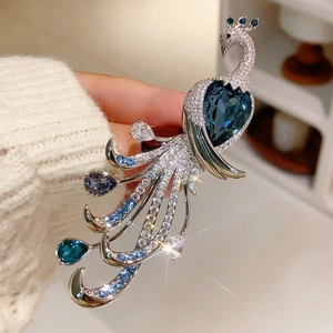 Macro view of peacock brooch featuring silver alloy and vibrant blue crystal feathers