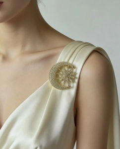 Detailed close-up of a sparkling crescent moon and star brooch on silk dress