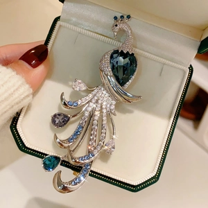 Macro shot of silver peacock brooch with heart-shaped blue gem and sparkling zircon details