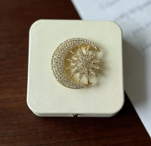Macro shot of gold sun and moon brooch with sparkling crystals on jewelry box