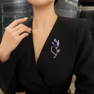 Detailed macro view of a luxury purple tulip brooch with faceted gem on a black blazer