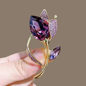 Detalle del elegante broche de tulipán con cristal morado y acabados en metal dorado