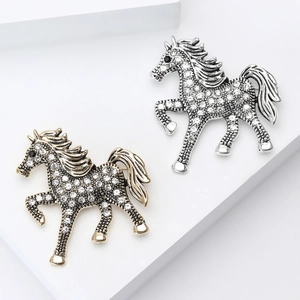 Close-up of gold and silver horse brooches with white rhinestones on white stands