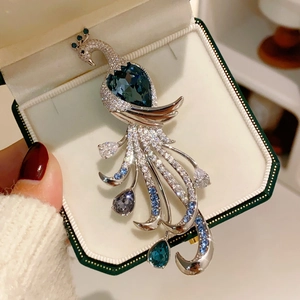 Exquisite peacock brooch with blue heart-shaped crystal on green jewelry box