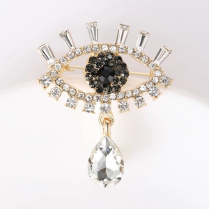 Detail view of Evil Eye brooch with gold setting, blue rhinestones, and pear pendant