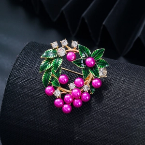 Vue macro d'une broche couronne de baies avec alliage doré, perles et feuilles d'émail