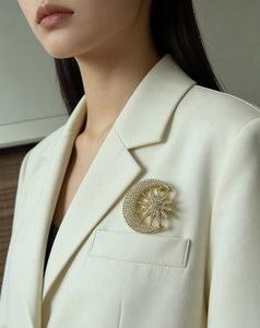 Close-up of a sparkling sun and moon brooch with crystals on a white blazer