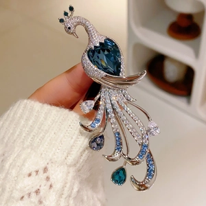 Macro shot of silver peacock brooch featuring deep blue heart crystal and inlaid gems