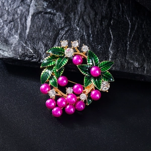 Détail macro d'une élégante broche couronne avec perles magenta et feuilles émaillées