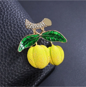 Détail de la broche fruit durian avec texture jaune, feuilles vertes et strass brillants