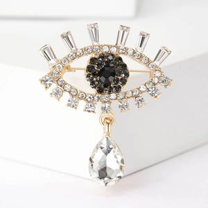 Macro shot of gold Evil Eye brooch with blue crystals and pear-cut drop pendant