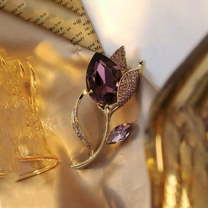 Detailed macro view of crystal tulip brooch with purple pear-cut stone on silk fabric