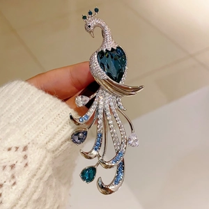 Detailed macro view of a luxury peacock brooch featuring heart-shaped blue crystals