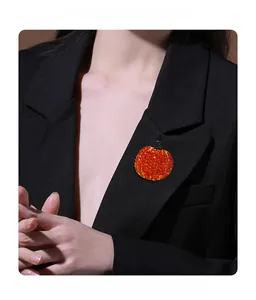 Funkelnde orange Kürbisbrosche mit Strasssteinen am Revers eines schwarzen Blazers